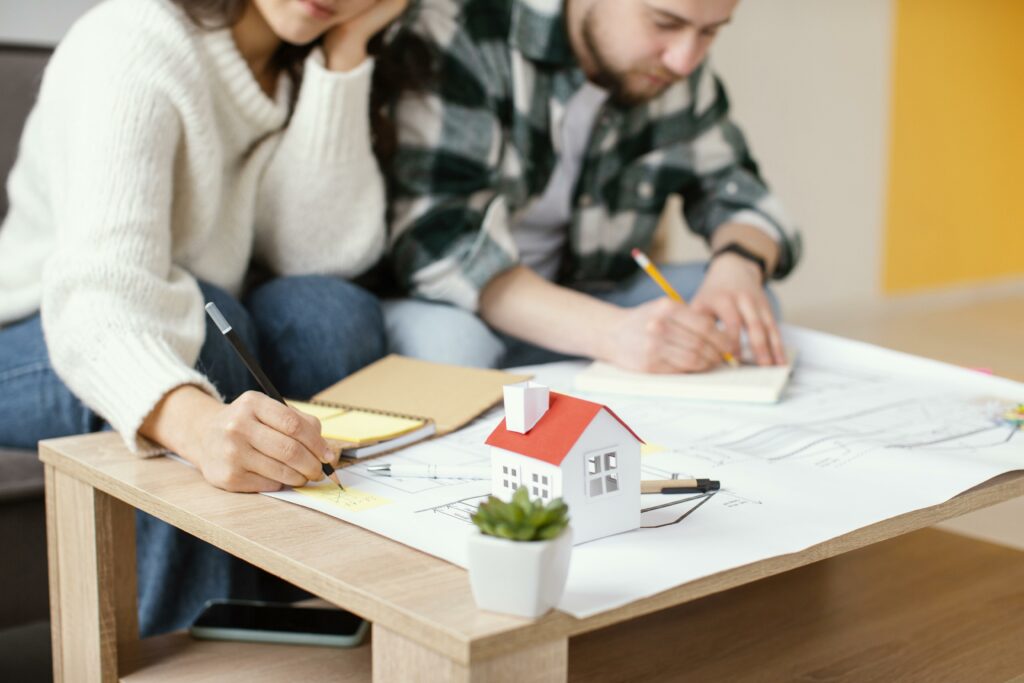 Deux jeunes gens qui dessinent les plans pour construire leur première maison.
